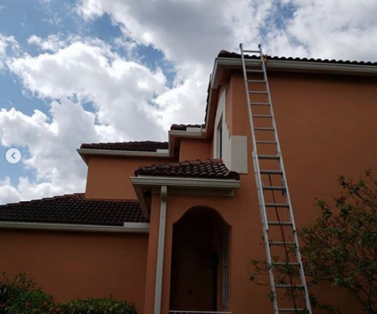 Extension ladder secured with Lock Jaw Ladder Grip on a two-story house, ensuring safety for roofing, repairs, and maintenance.