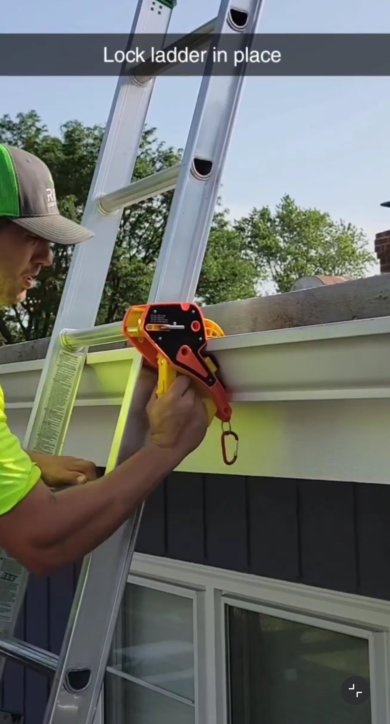 Worker using a Lock Jaw Ladder Grip to secure a ladder to a gutter for safe roof access and stability.