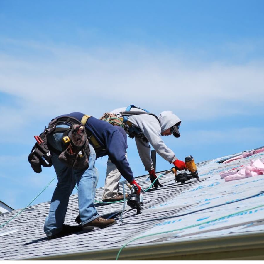 Roofers repairing a roof after storm damage