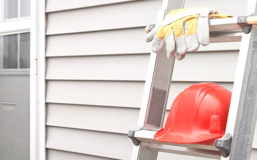 Extension ladder set against a house wall ready for a roof inspection