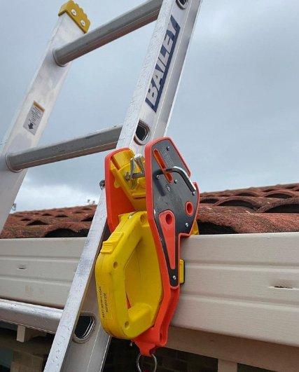 A gutter clamp securing the ladder at the eave