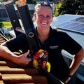 An electrical contractor with a gutter clamp and ladder on a tiled roof