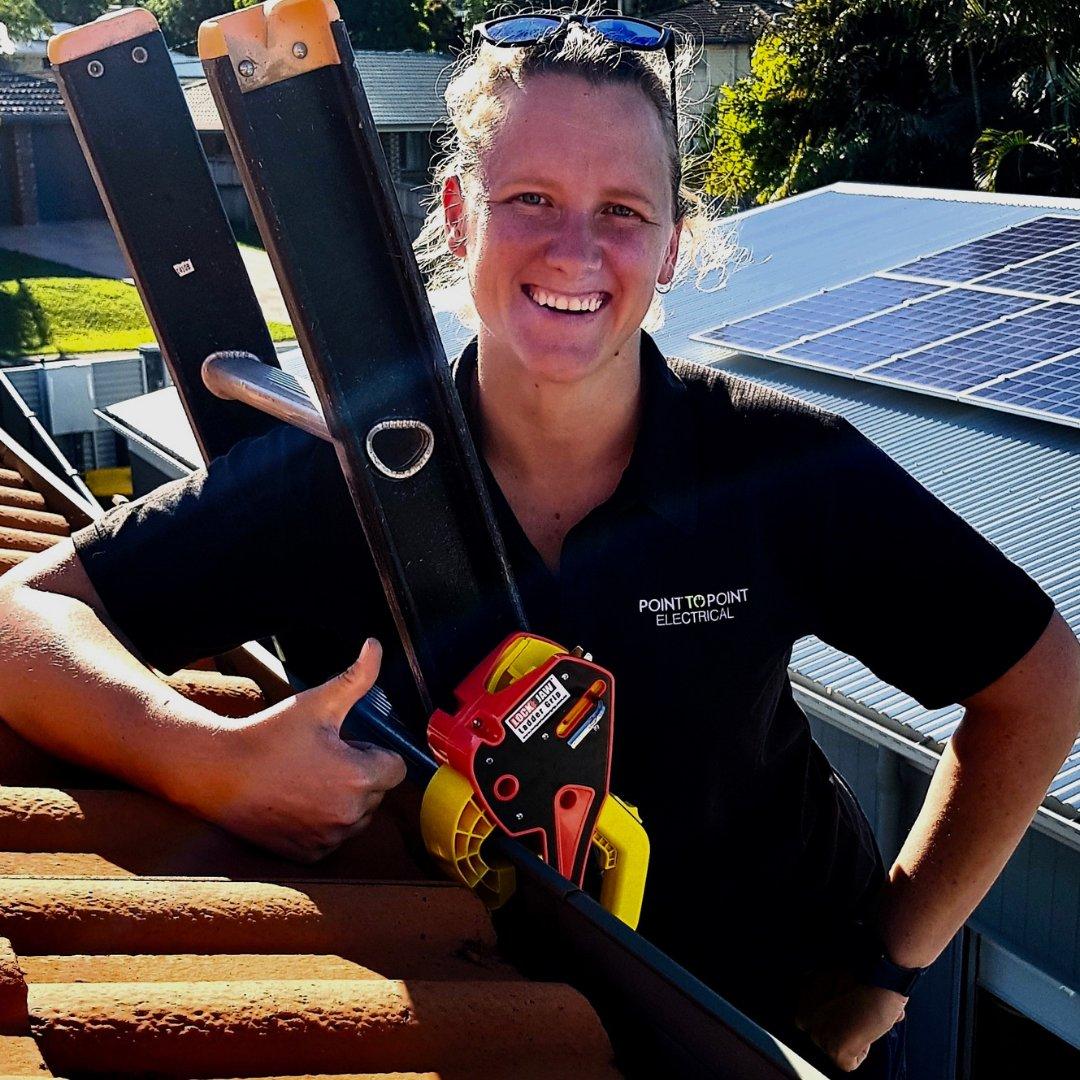 An electrical contractor with a gutter clamp and ladder on a tiled roof