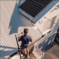 Climbing onto a metal roof with the ladder secured at the gutter