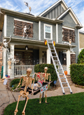 Halloween-decorated house with skeleton props and a ladder showing Lock Jaw grips at the gutter