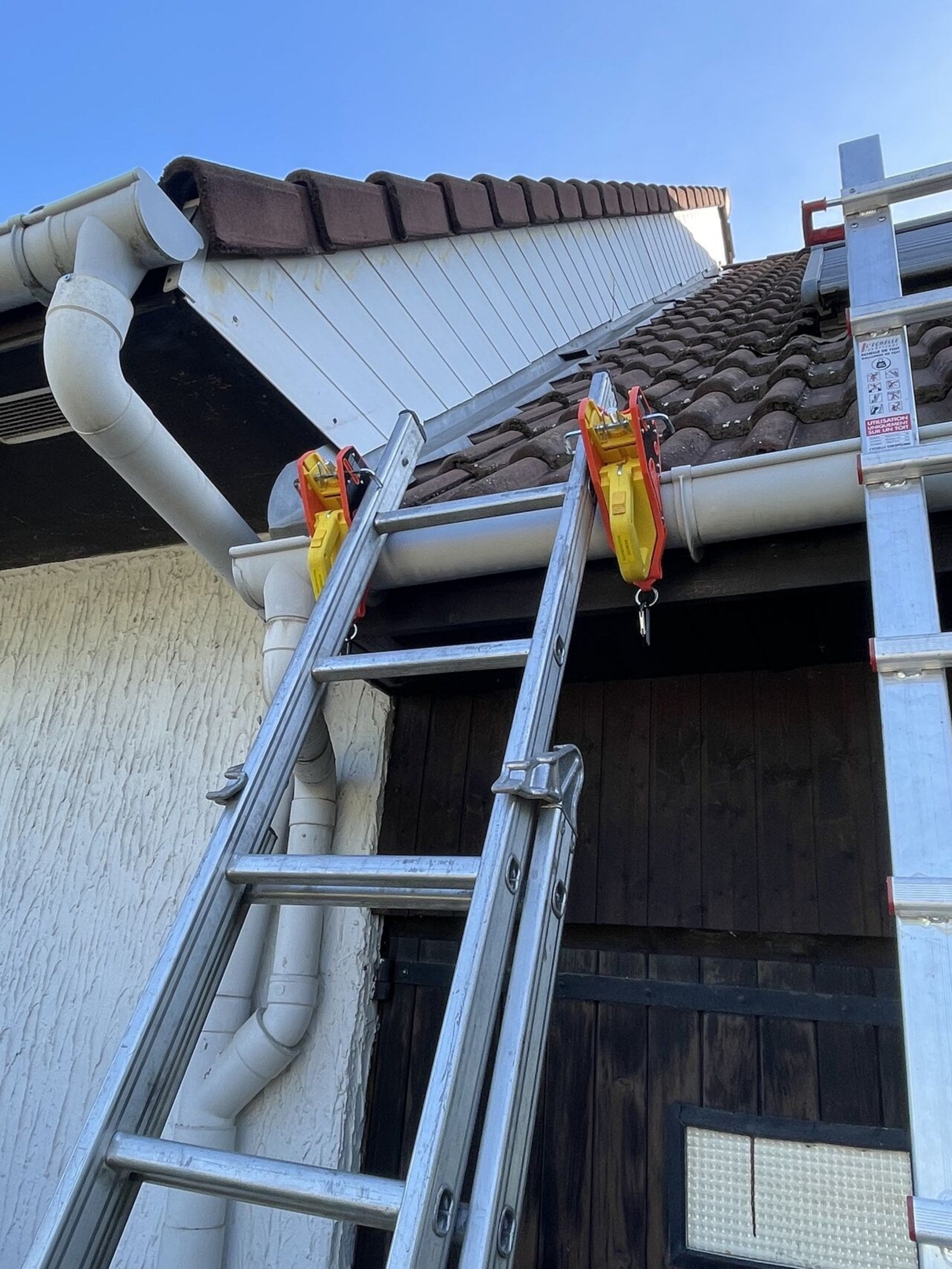 Two extension ladders secured to a roofline with Lock Jaw Ladder Grips