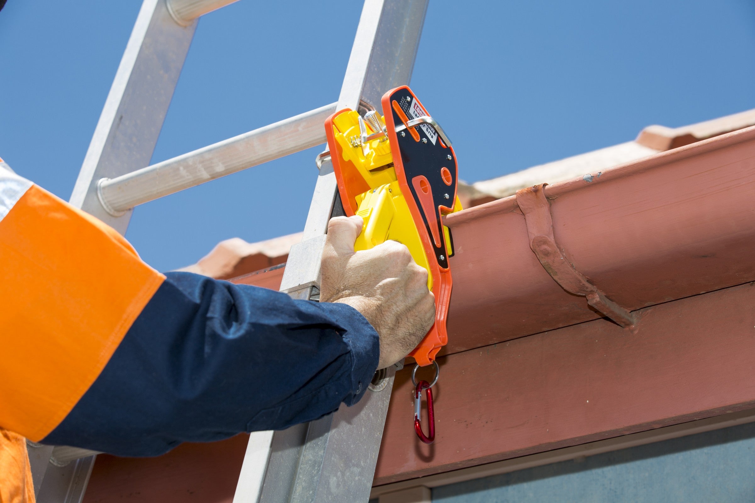A gloved hand clamping a Lock Jaw Ladder Grip onto a gutter