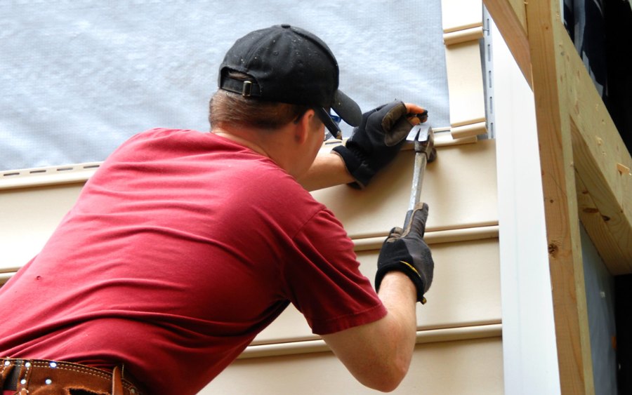 Technician working along the siding line of a house from a ladder
